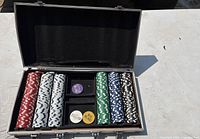 Casino chip set in open aluminium case showing red, white, green, blue, and black poker chips with four related buttons.