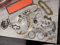 Full view of assorted jewelry items laid out on table showing variety including rings, bracelets, chains, pendants, and earrings