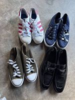 Photo showing four pairs of shoes: white/pink Adidas sneakers (size 7), green woven sneakers (size 7), black slip-on shoes (size 9), and navy blue Guess sneakers (size 9M).