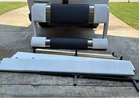 Disassembled queen size bed frame parts arranged on driveway including headboard, footboard, side rails, and metal support bars.