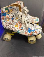 Side view of left roller skate showing colorful graffiti-style design and beige wheels.
