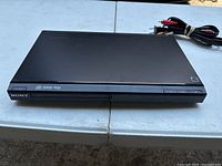 Front view of the black Sony DVD player showing disc tray and front panel buttons.