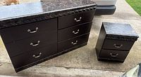 Wooden dresser with six drawers and matching nightstand with two drawers, black marble-patterned finish on tops.
