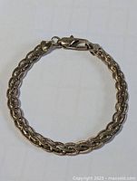 Full bracelet in circular form showing braided chain and clasp