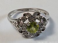 Top view of sterling silver ring showing green center stone and floral halo