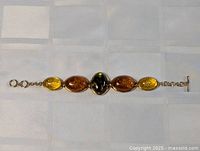 Entire bracelet laid flat showing five amber cabochons and toggle clasp