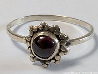 Front view of sterling silver ring showing red cabochon and floral bezel