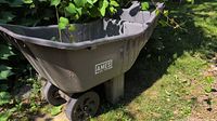 Side view showing Ames logo on gray plastic wheelbarrow body and plastic wheels