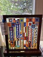 Full front view of framed wood and glass panel with multicolored geometric design