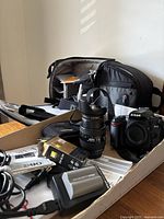 Tray with camera body, lens, charger, battery, filters, hood, strap and travel case