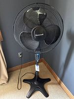 Full view of the Honeywell Quiet Set black floor fan showing four blades, circular grill, and control panel on pole.