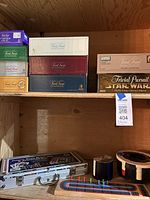 Shelf with multiple boxed editions of Trivial Pursuit including Star Wars and TV edition card set.