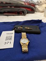Overview of all items on blue cloth: Bulova gold-tone watch, blue enamel Masonic ring, gold-tone tie pin.