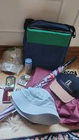 Photo showing assortment of golf accessories including hats, umbrella, golf tees, picks, markers, rain poncho, and carrying bag with seat cushions.