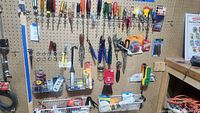 Wide view of a pegboard wall with various hand tools including screwdrivers, pliers, measuring tape, and small hardware items in baskets.