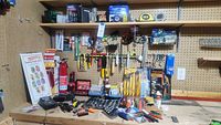 Wide view of various hand tools, sockets, screwdrivers, wrenches, fire extinguisher, battery tester, saw blades arranged on pegboard and shelf