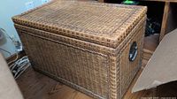 Full view of the rattan storage bench showing overall size, hinged lid, and woven construction.