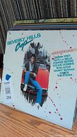 Photo of Beverly Hills Cop soundtrack vinyl album cover featuring artist list including Glen Frey, Patti LaBelle, and others.