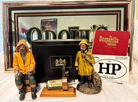 Wide shot of all items included in the lot showing the Gasparilla Cookbook, Hyde Park decal, two ceramic fisherman figurines, O’Doul’s bar mirror, and decorative cigar box.