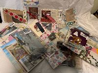Photo showing multiple sealed grab bags filled with vintage craft items including paper cutouts, beads, and ephemera spread out on a fabric background.