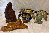 Five vintage mid century modern decor items grouped on white cloth including wooden monkey on stump, gold leaf wall ornaments (owl and bird), ceramic kids figurine, wooden tray.