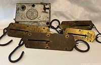 Photo showing four brass hanging scales with hooks, each with distinct scale markings and metal ring handles.