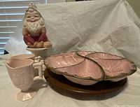 Group photo showing pink milk glass sugar bowl and milk jug, ceramic dwarf figurine, pink gold California Pottery dish on a dark brown lazy Susan base.