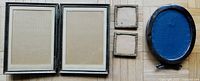 All five antique photo frames shown together on wooden floor: oval frame, twin hinged frame, and three small square frames