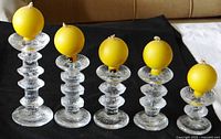 Wide shot showing all five crystal candle holders with handmade yellow spherical candles on top, arranged by descending height.