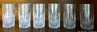 Front view of all six tall crystal glasses lined up, showing clear diamond and vertical cut patterns.