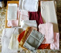 Variety of folded linen fabrics in different colors and textures placed on a wooden table.
