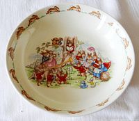 Top-down photo showing entire bowl interior with a colorful Bunnykins illustration of rabbits playing music and singing outdoors, bordered by a rim of running rabbit pattern.