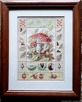 Full view of the framed cross-stitch artwork showing the entire piece including the wood frame and matting.