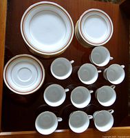 Top down view of cups and plates stacked, showing sets of 10 units each for cups, saucers, dinner plates, and cake plates.