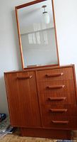 Angled front view of dresser with mirror atop