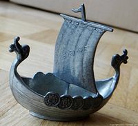 Front angle showing Viking ship shape with shields and dragon-head design, sail with 'SVERIGE' engraved