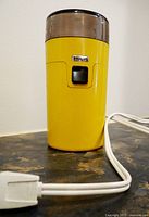 Yellow Philips coffee grinder with plug and visible brand logo on front.