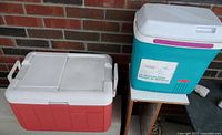 Both Rubbermaid and Coleman coolers shown side by side on a small table against brick wall.