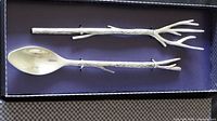 Two-piece salad serving set displayed in original box. Pieces have handles resembling tree branches with a smooth spoon and fork end.