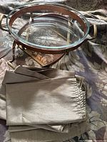 Folded sage green cloth napkins with a glass and metal tray in the background.