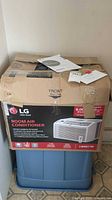 Original box of LG room air conditioner model LW6017R with product information and manual on top.