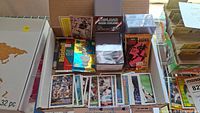 Box containing assorted baseball cards including loose cards and unopened packs, with some card protection holders