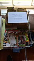 Multiple stacks of loose baseball cards on a wire rack with a handwritten note describing the lot.