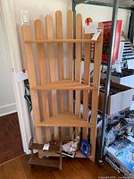 Front view of the unfinished picket fence style wooden corner shelf showing three triangular shelves and vertical slat backrest.