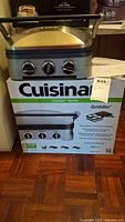 Cuisinart Griddler unit placed on top of its original product box showing front view and model details with box graphics.