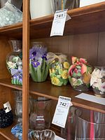 Six hand painted vases and one bottle with floral and ribbon decorations, signed by Catherine Connell, displayed on a wooden shelf.