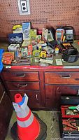 Full view of lot items on wooden workbench including multimeters, drill bits, staple boxes, hardware packages, and coils of tubing.