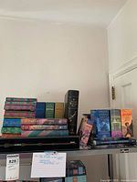 Wide view of multiple Harry Potter books stacked including Tales of Beedle the Bard tall boxed edition and Harry Potter collectible wand in display case.
