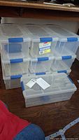 10 clear Sterilite Keepsake media storage containers stacked together showing blue locking handles and labels.