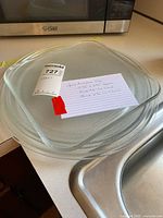 Three microwave trays stacked, showing the two largest trays distinctly with a note card identifying tray sizes and brand sticker on one tray.
